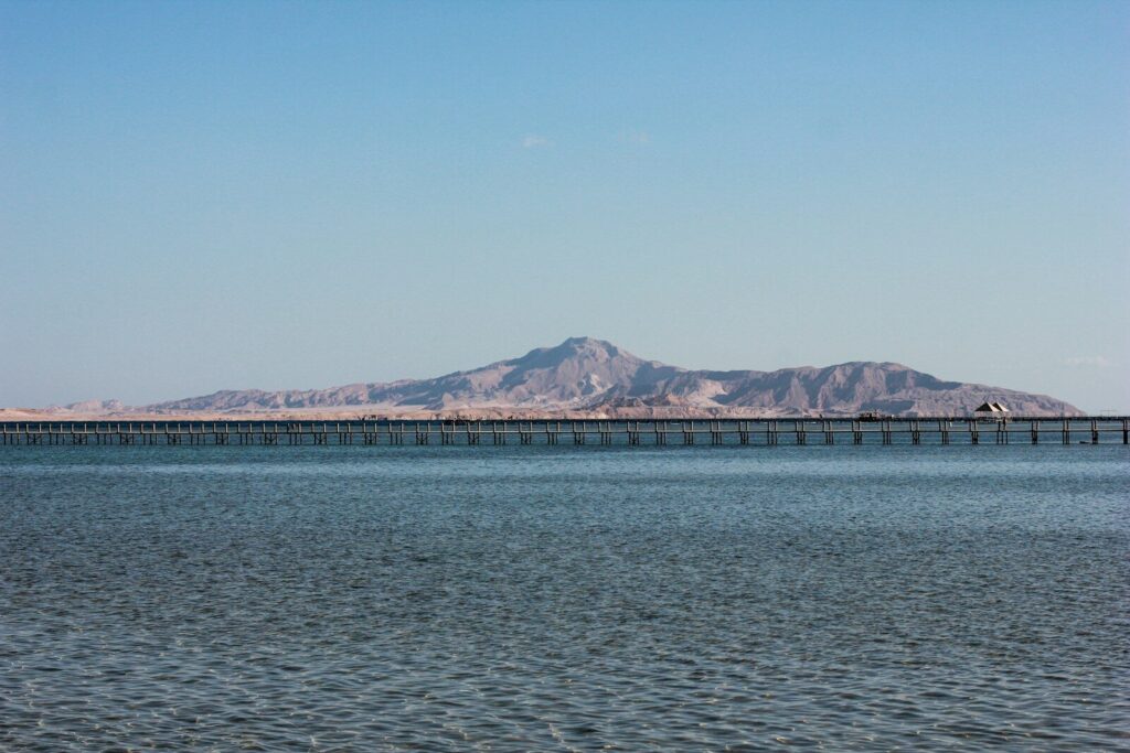 blue sea near mountain under blue sky during daytime