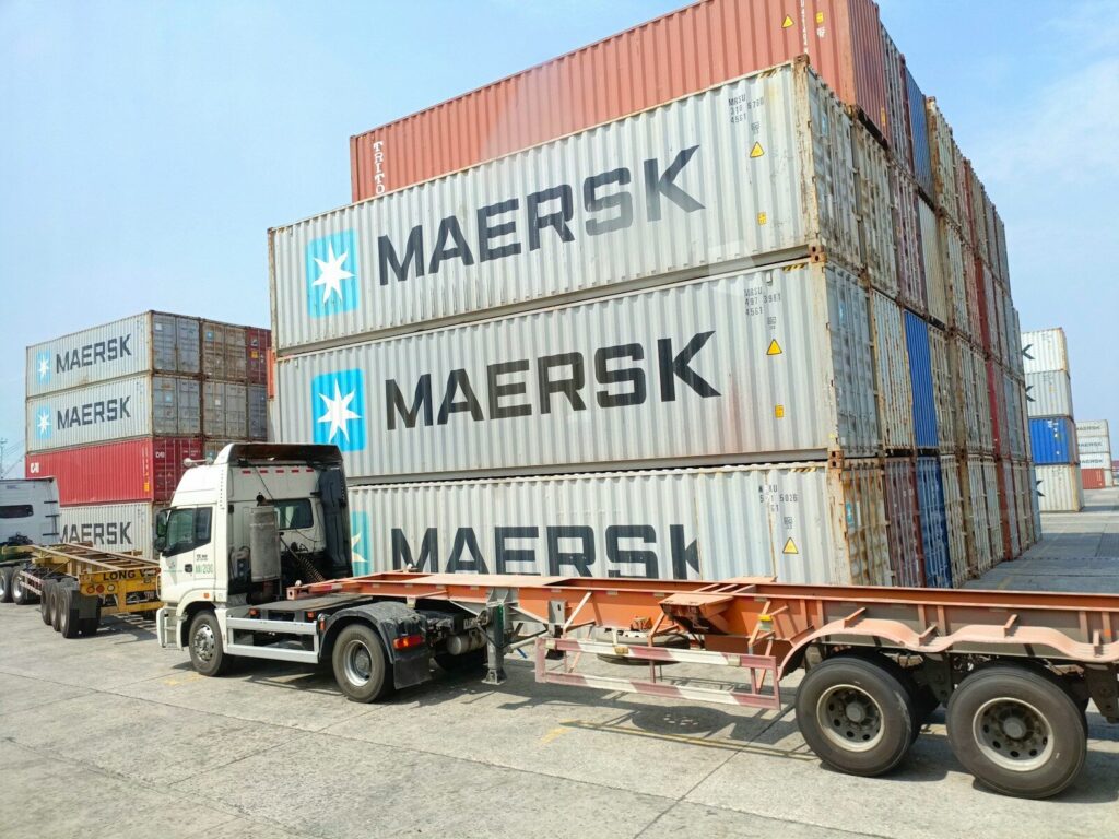 a semi truck is parked next to a large container