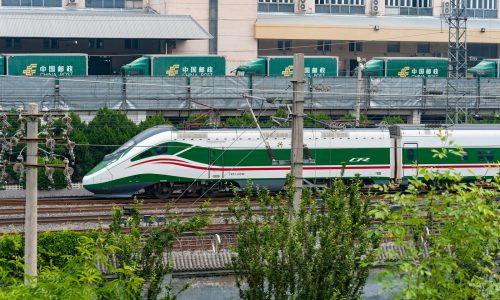 a green and white train traveling down train tracks
