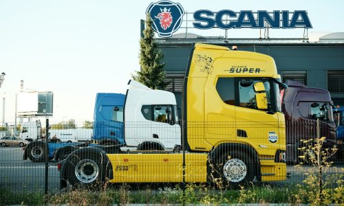 Yellow and blue trucks parked outside scania building